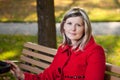 Blond woman in red coat holding handle or pram.