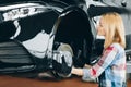 Blond woman replacing brakes of lifted automobile at auto repair garage Royalty Free Stock Photo