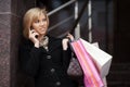 Blond woman with shopping bags calling on the phone Royalty Free Stock Photo