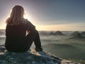 Blond woman sitting on edge of the mountain cliff against surise