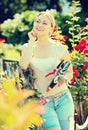 Blond woman taking care of red rose bushes Royalty Free Stock Photo