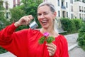 Blond woman watering with miniature can a flower and making funny face