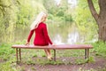 Blond woman wearing an office clothes sitting on a bench in the park near a lake. The picture reflects the return to natural life Royalty Free Stock Photo