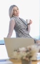 blond woman wearing office clothes sitting on a windowsill with cup of coffee getting rest. coffee break, hard working