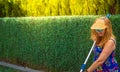 Blond woman with wet hair wearing sun visor, sunglasses, happy and smiling in flowery colorful summer dress holding pool cleaner Royalty Free Stock Photo