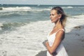 Blond woman in white dress standing by the ocean Royalty Free Stock Photo