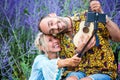 Blond woman and man in wheelchair with guitar taking  selfie in front of field of flowers Royalty Free Stock Photo