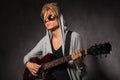 Blond young man with messy hair playing guitar in studio Royalty Free Stock Photo