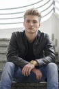 Blond young man sitting on stairs outside