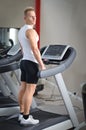 Blond young man standing on treadmill Royalty Free Stock Photo