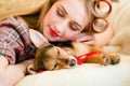Blond young woman with curlers sleeping with her little puppy Royalty Free Stock Photo