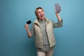 blond young woman holding a plastic card mockup and a smartphone to pay for purchases online Royalty Free Stock Photo