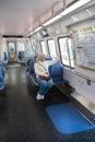 Blonde adult woman in an empty Washington subway train wearing blue jeans while waving her hand out the window