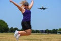 Blonde adult woman at Gravelly Point Park in Washington DC jumps as an airplane flies in for a landing at the DCA Reagan Royalty Free Stock Photo