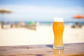 blonde ale in a pilsner glass, golden color, next to a sunny beach scene