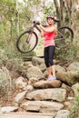 Blonde athlete carrying her mountain bike over rocks Royalty Free Stock Photo