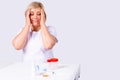 Blonde attractive woman is shocked and worried holding her head and looking at the test jars on the table near her.