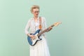 Blonde attractive young adult hipster woman with eyeglasses plating guitar like star.