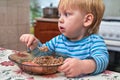 Blonde babe eats with a spoon from the porridge plates in the kitchen