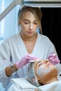 Blonde beautician cleaning female face with cotton pads at aesthetic clinic. Royalty Free Stock Photo