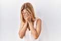 Blonde beautiful young woman standing over white isolated background with sad expression covering face with hands while crying Royalty Free Stock Photo