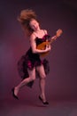 Blonde, in black dress with red flounces, with a mandolin in her hands on a Burgundy background of the Studio Royalty Free Stock Photo