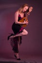 Blonde, in black dress with red flounces, with a mandolin in her hands on a Burgundy background of the Studio Royalty Free Stock Photo