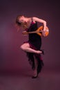 Blonde, in black dress with red flounces, with a mandolin in her hands on a Burgundy background of the Studio Royalty Free Stock Photo