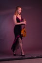 Blonde, in black dress with red flounces, with a mandolin in her hands on a Burgundy background of the Studio Royalty Free Stock Photo