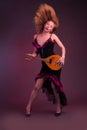 Blonde, in black dress with red flounces, with a mandolin in her hands on a Burgundy background of the Studio Royalty Free Stock Photo