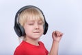 Blonde boy headphones with pleasure of listening to music. Portrait of children with headphones on white background Royalty Free Stock Photo