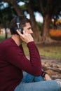 Blonde boy listening to music on wireless headphones sitting on the floor without looking at the camera. Enjoying the song. Royalty Free Stock Photo