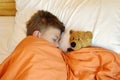 Baby boy asleep in bed under the covers. Lybia toy child