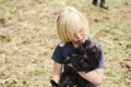 Blonde boy snuggling black Brussels Griffon puppy Royalty Free Stock Photo