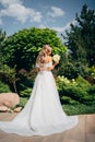 a blonde bride with bouquet Calla Lily in the park in a white long dress.