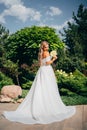 a blonde bride with bouquet Calla Lily in the park in a white long dress.