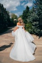 a blonde bride running down a path in the park in a white long dress. Royalty Free Stock Photo