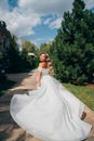 a blonde bride running down a path in the park in a white long dress. Royalty Free Stock Photo