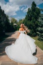 a blonde bride running down a path in the park in a white long dress. Royalty Free Stock Photo