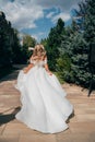 a blonde bride running down a path in the park in a white long dress. Royalty Free Stock Photo