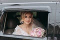 A blonde bride sits in a black car on her wedding day with a bouquet. Royalty Free Stock Photo