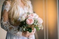 Blonde bride wearing an elegant white wedding dress and holding a bouquet of beautiful pink roses Royalty Free Stock Photo