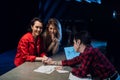 Blonde and brunette young girls choose tattoos together with a tattoo master with a short hairstyle and facial piercings Royalty Free Stock Photo