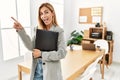 Blonde business woman at the office with a big smile on face, pointing with hand finger to the side looking at the camera Royalty Free Stock Photo