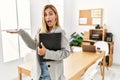 Blonde business woman at the office pointing aside with hands open palms showing copy space, presenting advertisement smiling Royalty Free Stock Photo