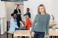 Blonde business woman smiles at camera with colleagues working in background Royalty Free Stock Photo