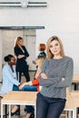 Blonde business woman smiles at camera with colleagues working in background Royalty Free Stock Photo