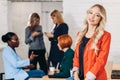 Blonde business woman smiles at camera with colleagues working in background Royalty Free Stock Photo