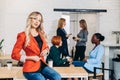 Blonde business woman smiles at camera with colleagues working in background Royalty Free Stock Photo