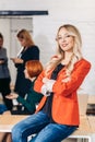 Blonde business woman smiles at camera with colleagues working in background Royalty Free Stock Photo